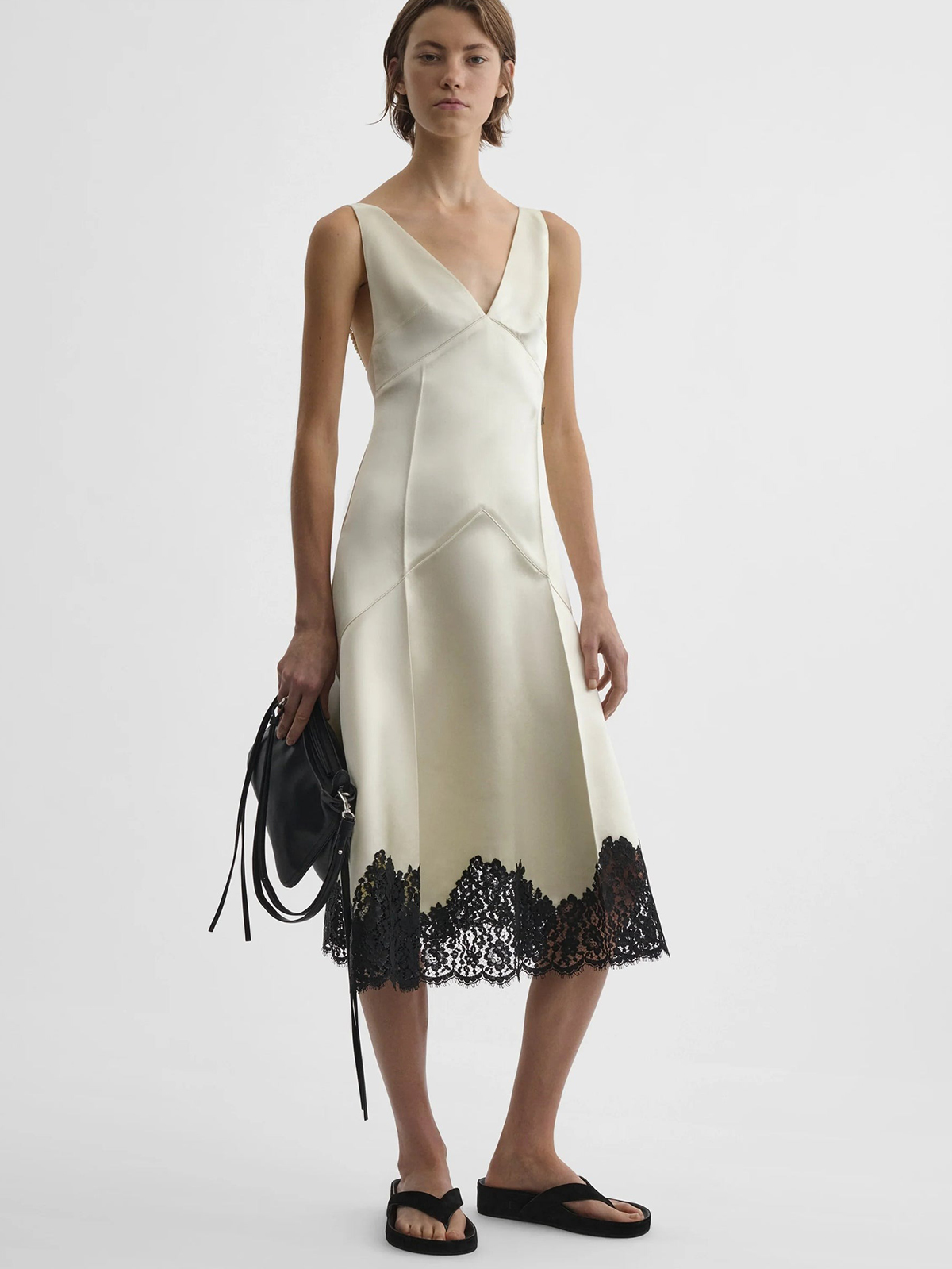 A Phoebe Philo model wearing a soft-yellow satin dress with black lace trim and flip flops.