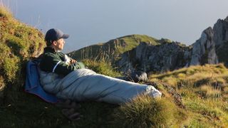 Man in Rab Mythic 400 sleeping bag in the mountains