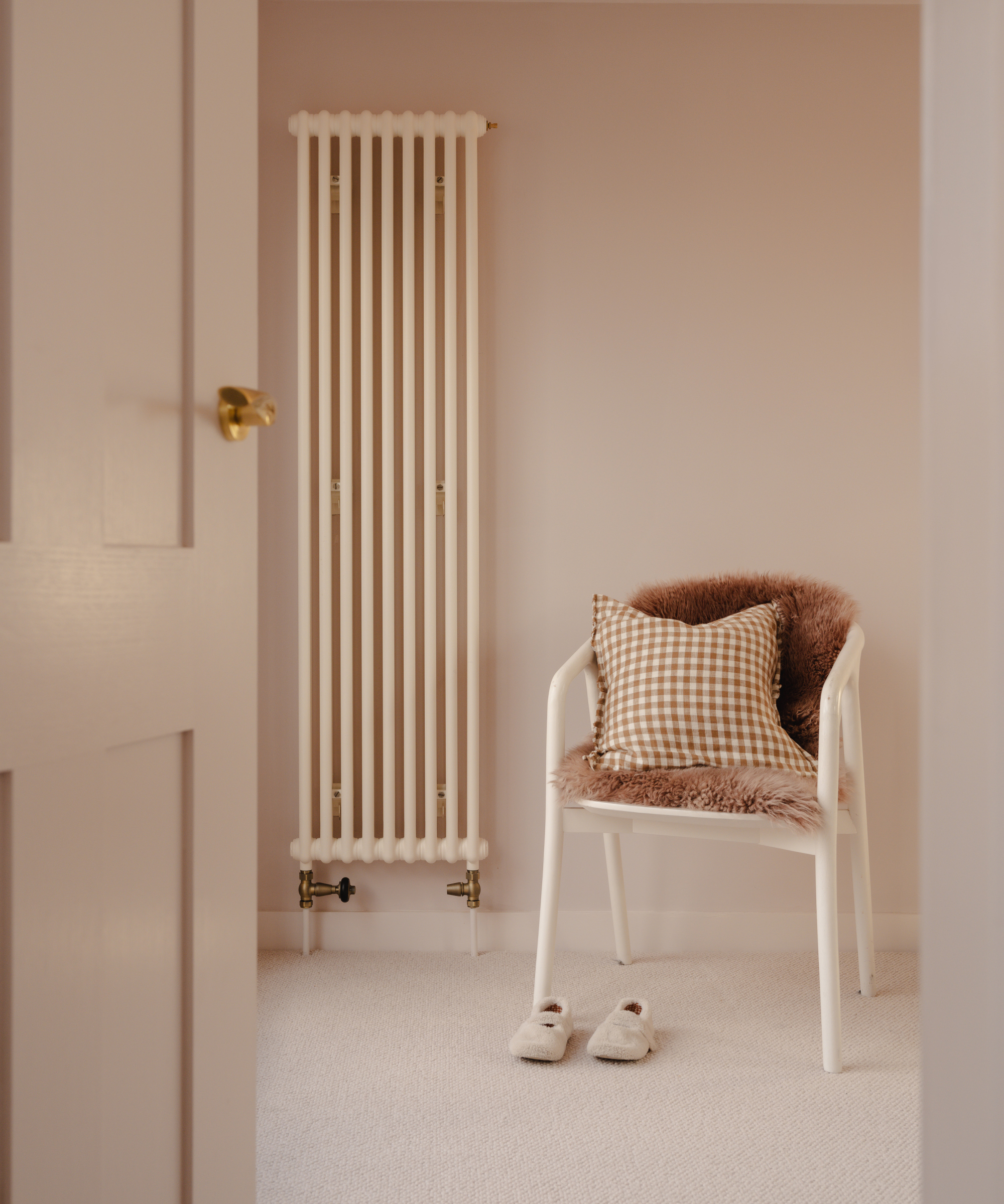 Tall slim column radiator on wall next to white chair
