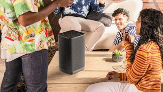 hero image for best bluetooth speakers buying guide showing Ultimate Ears Hyperboom on a coffer table surround by young people