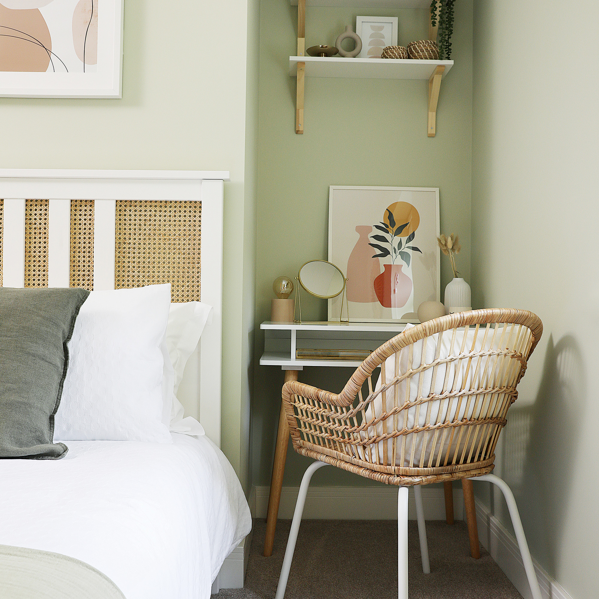 green bedroom with small dressing station and woven chair in a nook beside the bed