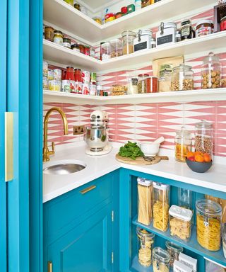 Kitchen pantry with white shelving, blue cabinets and pink and white tiled backsplash