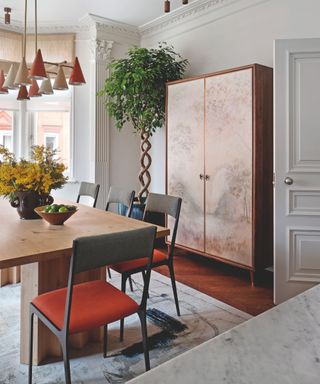 dining room with wooden rectangular table and orange upholstered chairs and freestanding cupboard