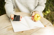 young girl with cell phone, diary and green apple