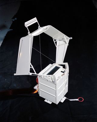 Lunar Surface Gravimeter appears as a large white box with a "squashed" hexagon shape attachment at the top with a handle.
