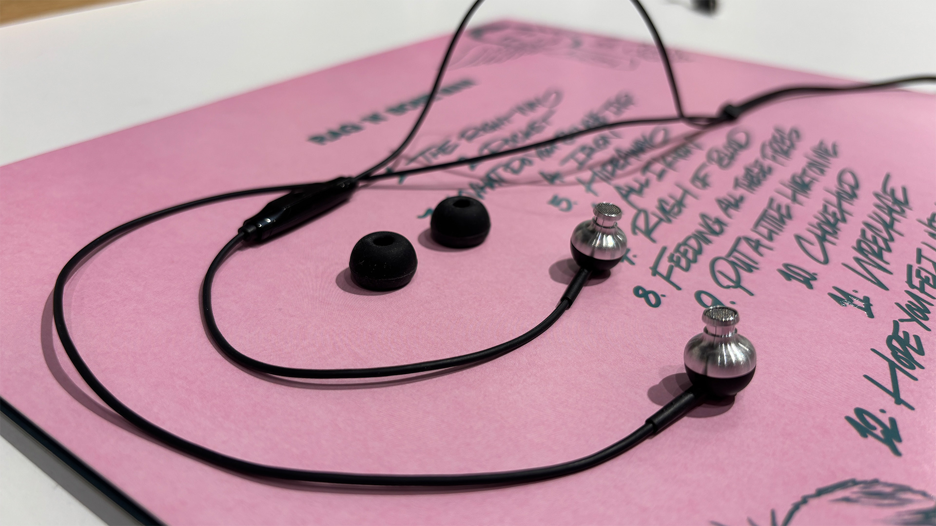 Sennheiser CX 80U wired earbuds lying on pink surface with eartips detached