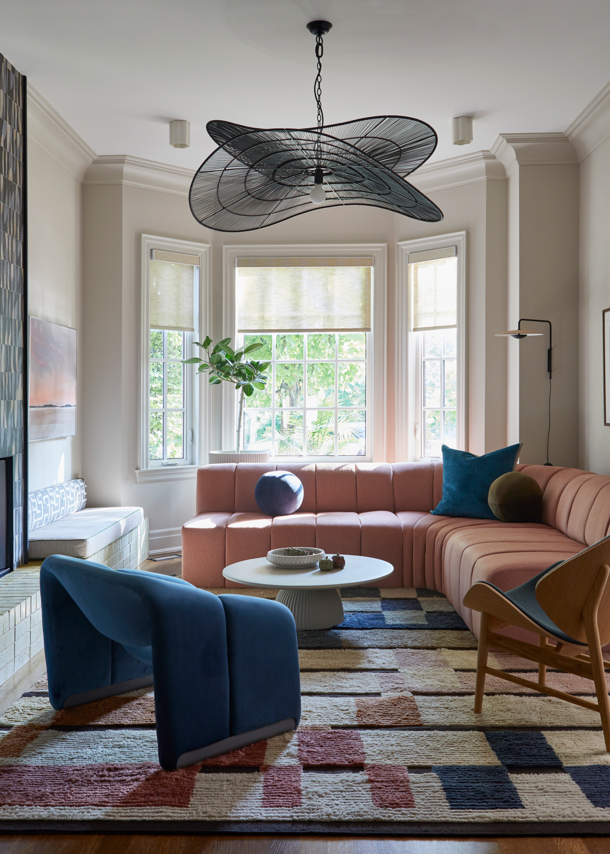 a living room with a pink and blue rug, sofa, and chair