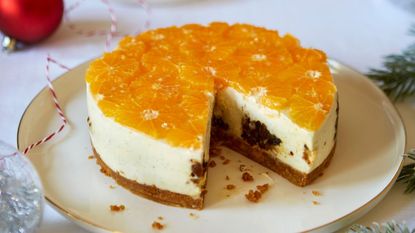 A Christmas pudding cheesecake on a plate with a slice cut out of it