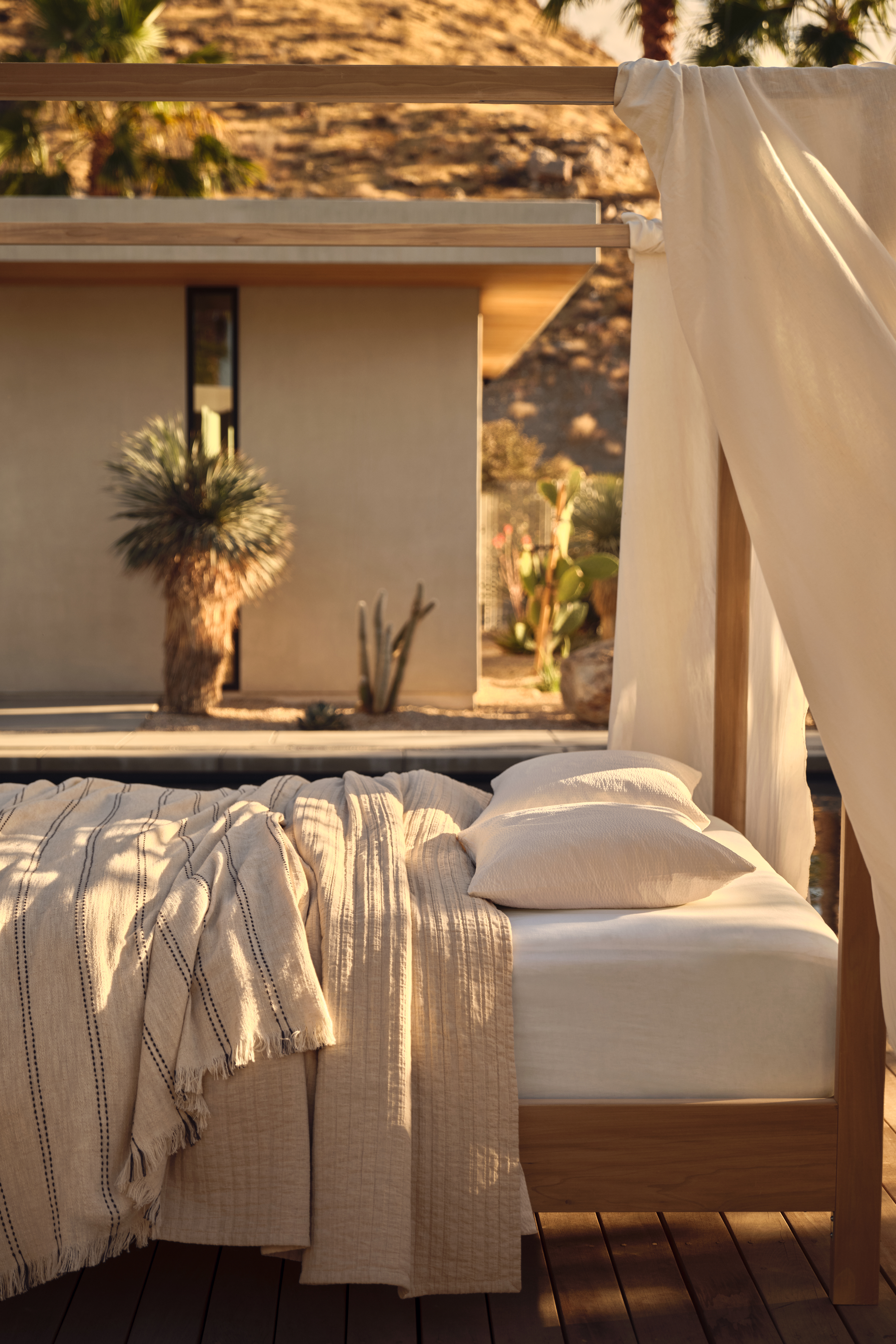 a bed outside dressed with linens and drapes on a four poster bed