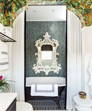 Green tiled walls, white mirror, black bath, back and white tiled floor