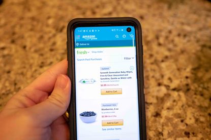 Close-up of hand of a man using the Amazon mobile app to purchase household supplies from Amazon Prime, San Ramon, California