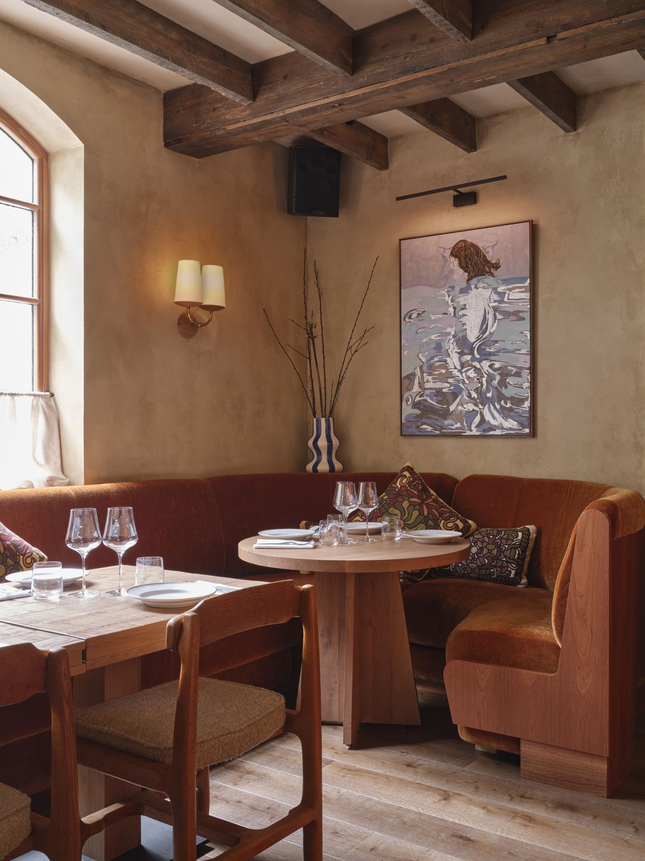 A warmly suffused, atmospheric restaurant features farmhouse-inspired interiors dotted in wooden details, tiled surfaces, and sandy tones.