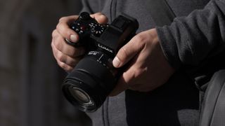 Panasonic Lumix S 28-200mm lens attached to a camera and held in a pair of hands