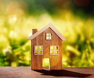 small wooden house model in front of blurred green grass background