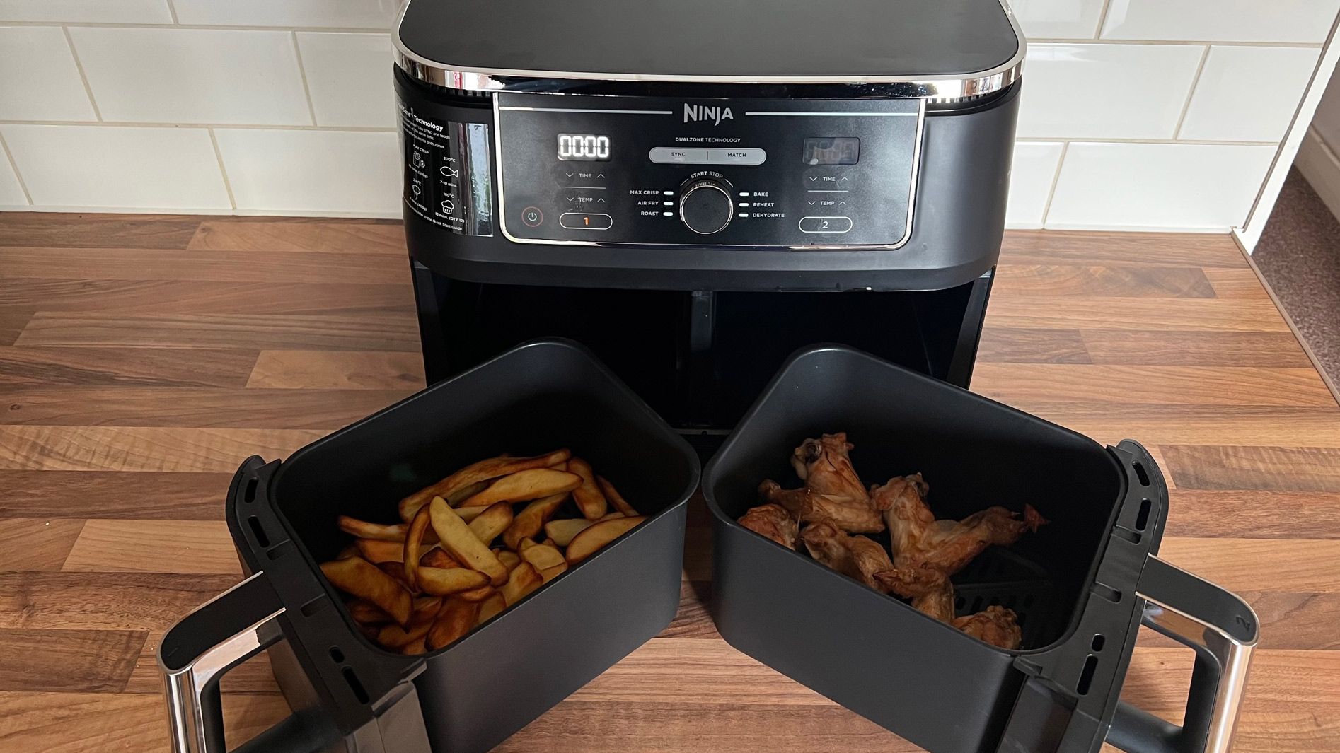 The Ninja Foodi Max AF400UK dual zone air fryer having been used to cook fries and chicken wings at the same time