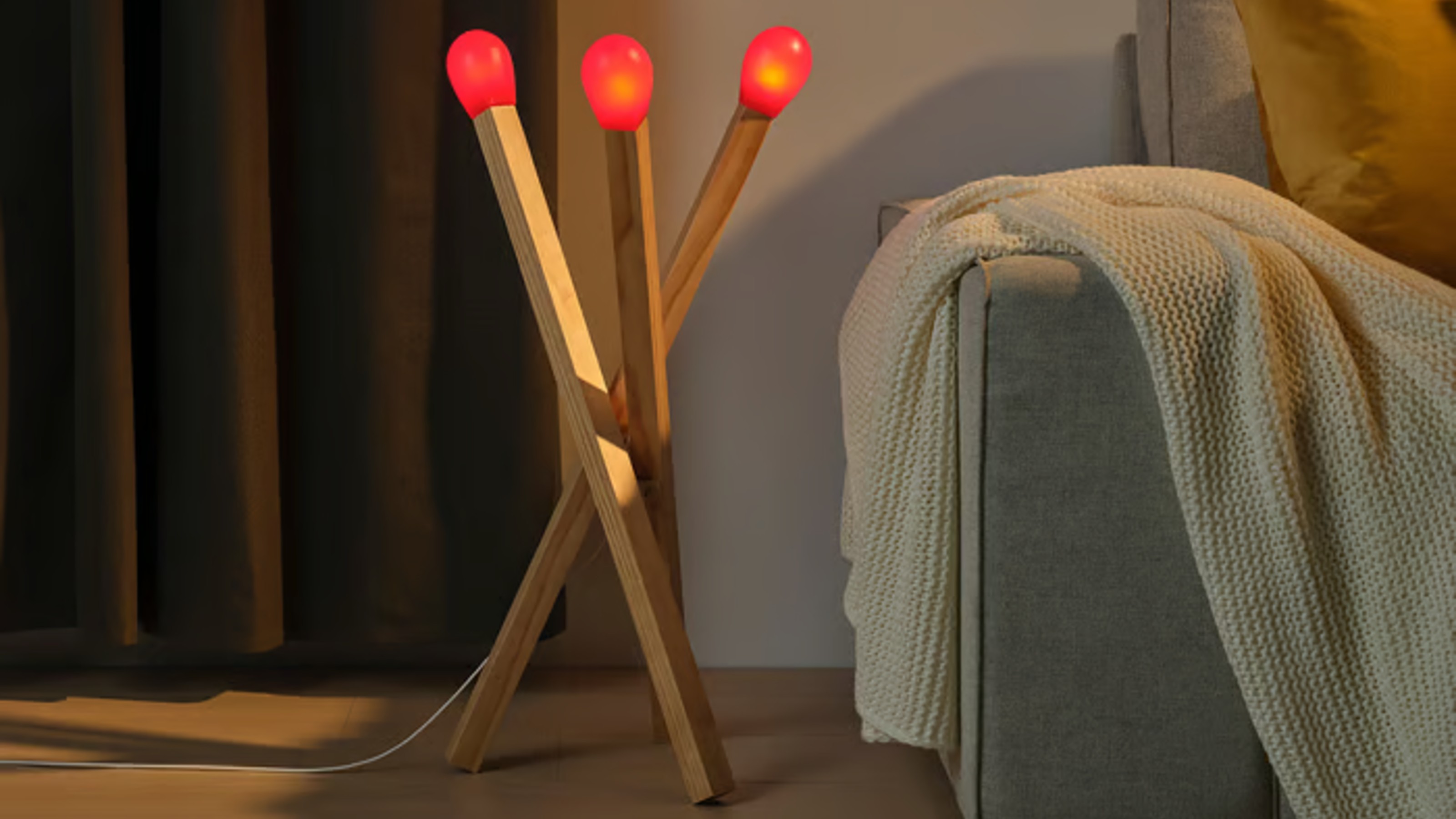 IKEA STRALA matchstick lamp on the floor next to a grey sofa
