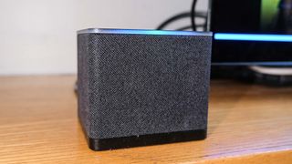 A close-up of the Fire TV Cube (2022) with its blue Alexa bar glowing