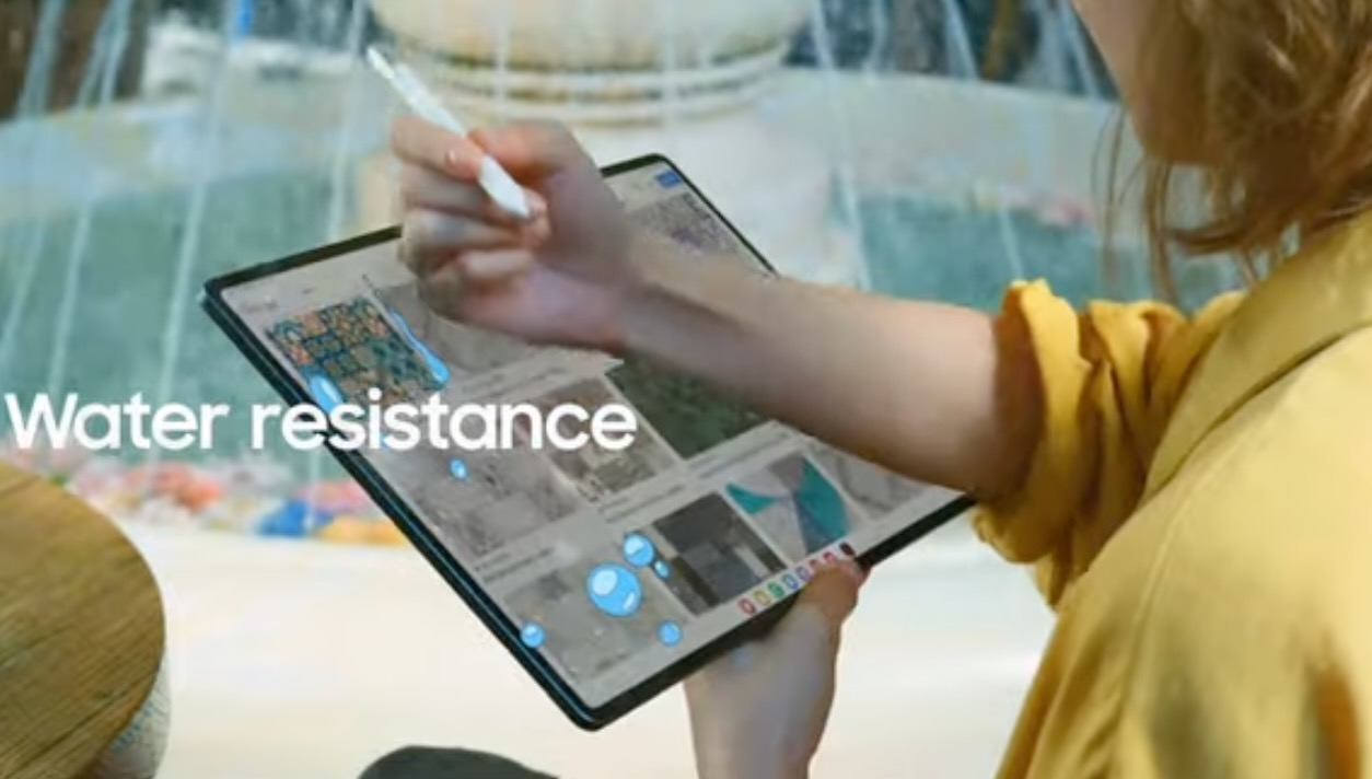 Screenshot of the Galaxy Unpacked July 2023 livestream showing a young woman wiping water off of the Galaxy Tab S9.