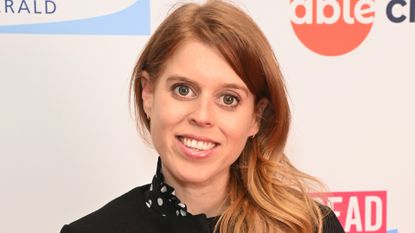 Princess Beatrice wearing a black jacket and polka dot dress smiling at the camera 