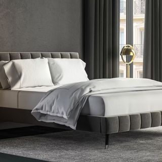 Valencia Queen Bed Frame with white bedding against a gray wall.