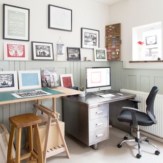 Home office with wall panelling, metal desk and artwork prints
