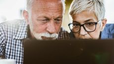 Mature couple with eyesight problems peering at a laptop.