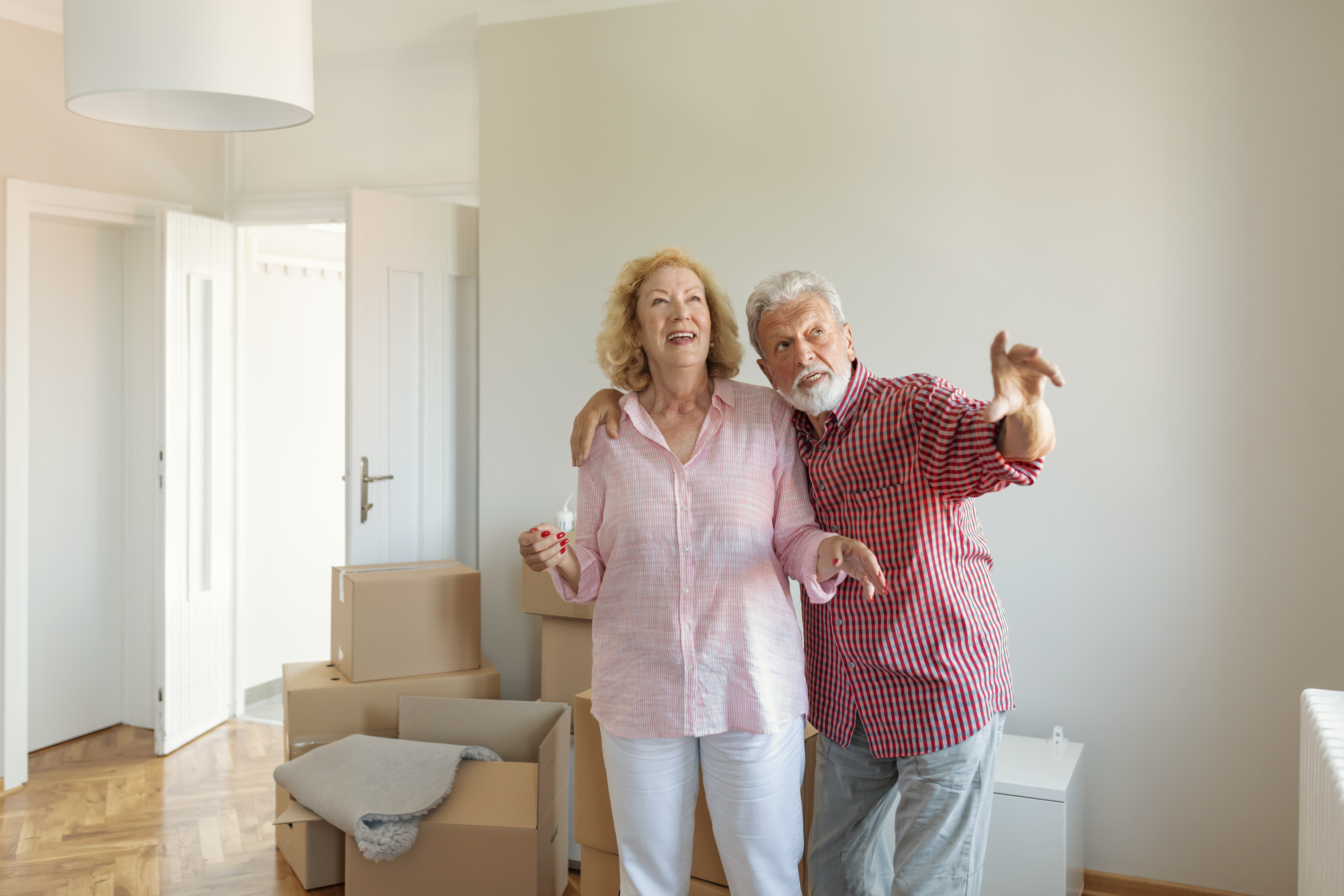 Senior Couple Carrying Boxes Into New Home on Moving Day. Elderly Couple Is Having Fun With Cardboard Boxes Into New Home Together