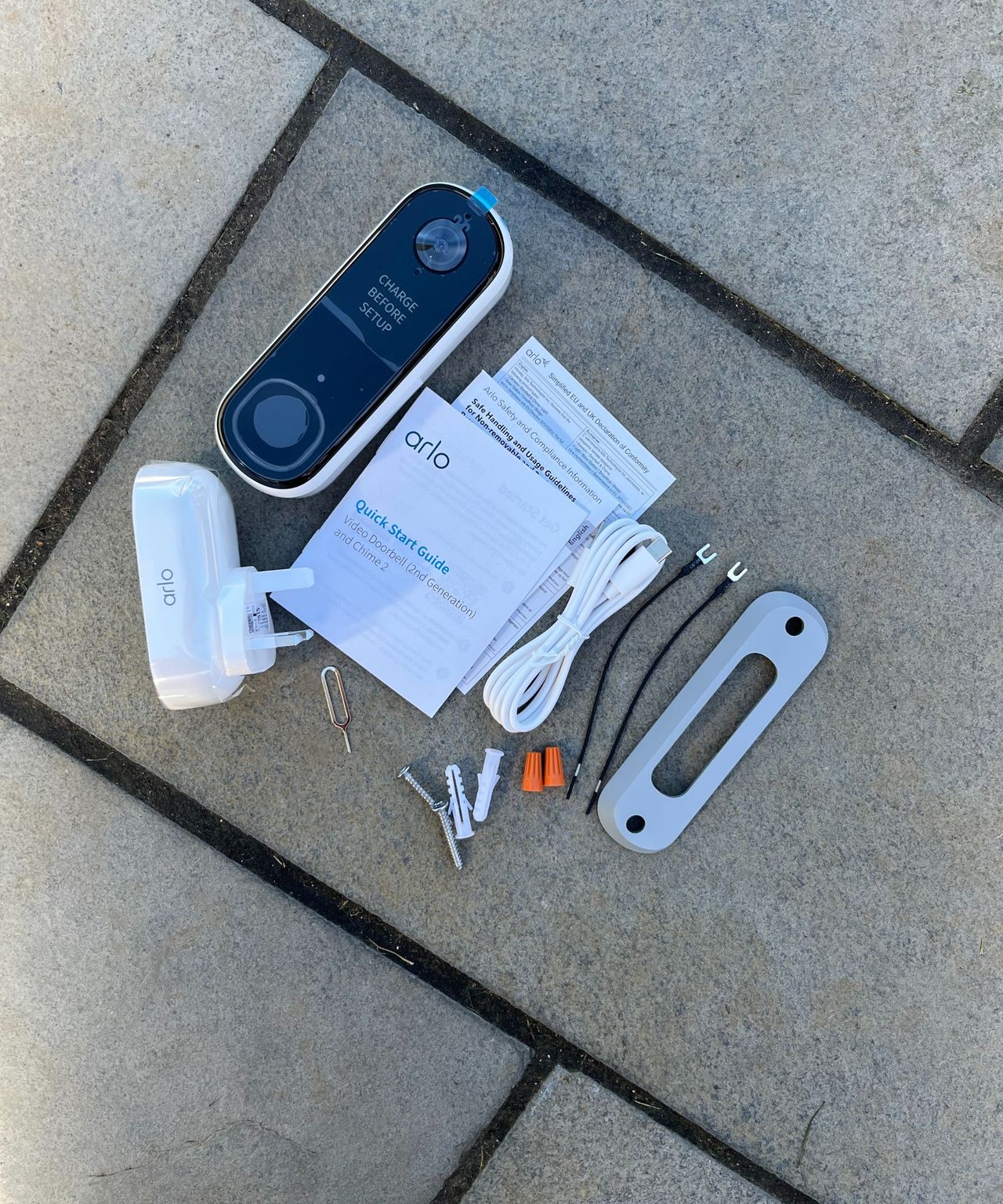 All parts for the Arlo 2K Wireless Video Doorbell laid out on tiled floor.