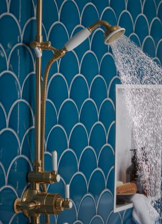 brass handheld shower with blue fan wall tiles