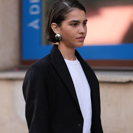 PARIS, FRANCE - SEPTEMBER 27: Guest is seen outside The Row show wearing silver earrings, black blazer, white. shirt underneath, black pants with wide leg and cut outs, red lace-up heels and a Gucci Jackie in brown with Gucci monogram during the Womenswear Spring/Summer 2024 as part of Paris Fashion Week on September 27, 2023 in Paris, France. 