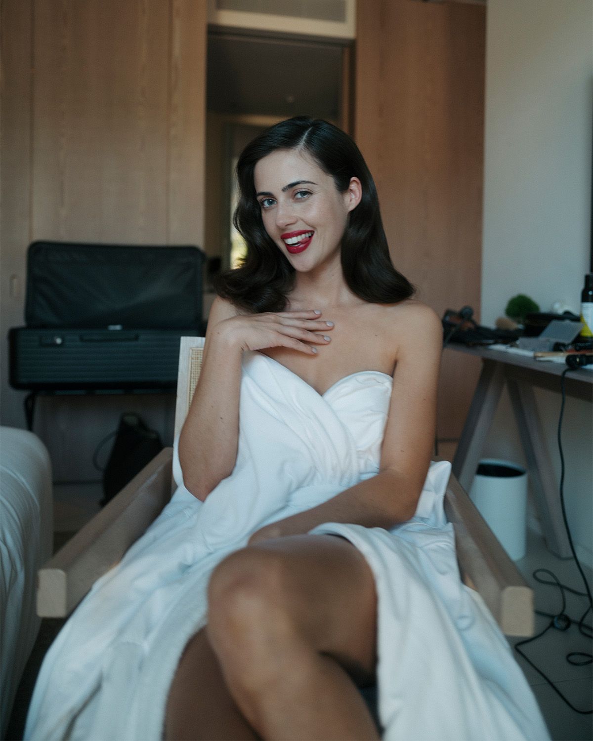 A photo of Lydia Peckham in the glam chair, her glam completed before the Nuremberg AFI Film Festival premiere. She is wearing a white robe and has soft curls and a deep red lip.