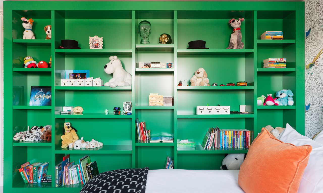 Toys stacked on built-in green shelving in a kid&#039;s bedroom