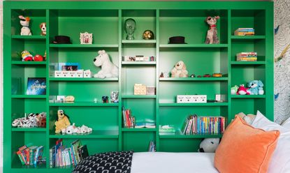 Toys stacked on built-in green shelving in a kid's bedroom