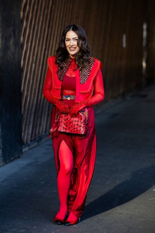 PARIS, FRANCE - MARCH 05: A guest wears red jacket gloves, skirt, tights outside Stella McCartney during the Womenswear Fall/Winter 2025/2026 as part of Paris Fashion Week on March 05, 2025 in Paris, France. (Photo by Christian Vierig/Getty Images)