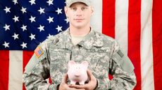 A soldier holds a piggy bank.