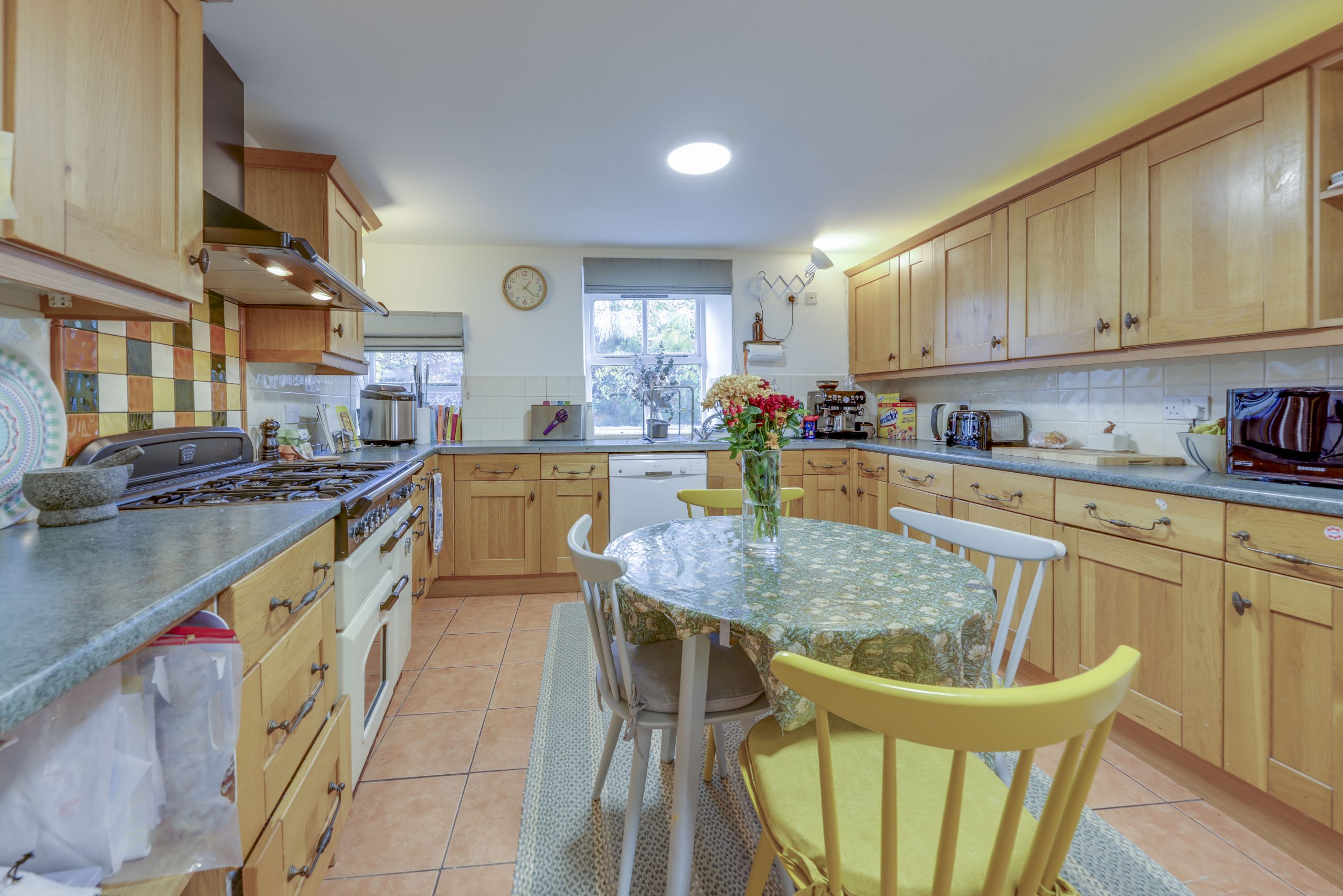 A country kitchen/diner with a round dining table and wooden units