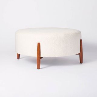 A round sherpa ottoman with wooden legs as the best Target furniture pieces.