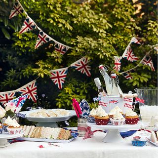 outdoor food buffet with white tablecloth union jack bunting cupcakes