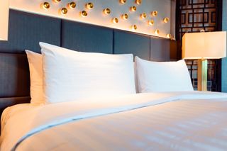 A large bed with white sheets on a blue bedframe inside a hotel room