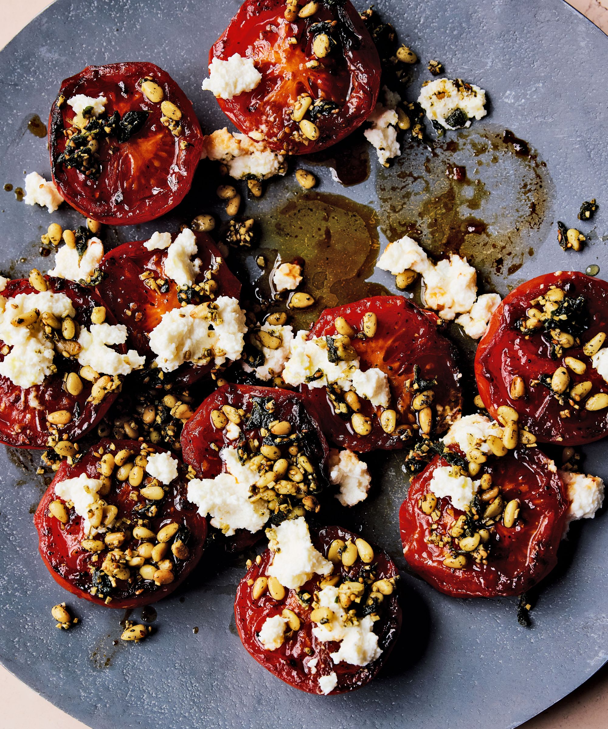 Pan fried tomatoes with halloumi and pine nuts on a plate