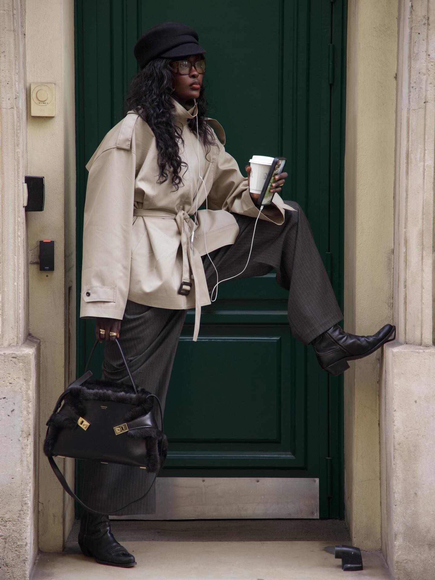 An image of @lefevrediary wearing a cropped trench coat with trousers and cowboy boots.