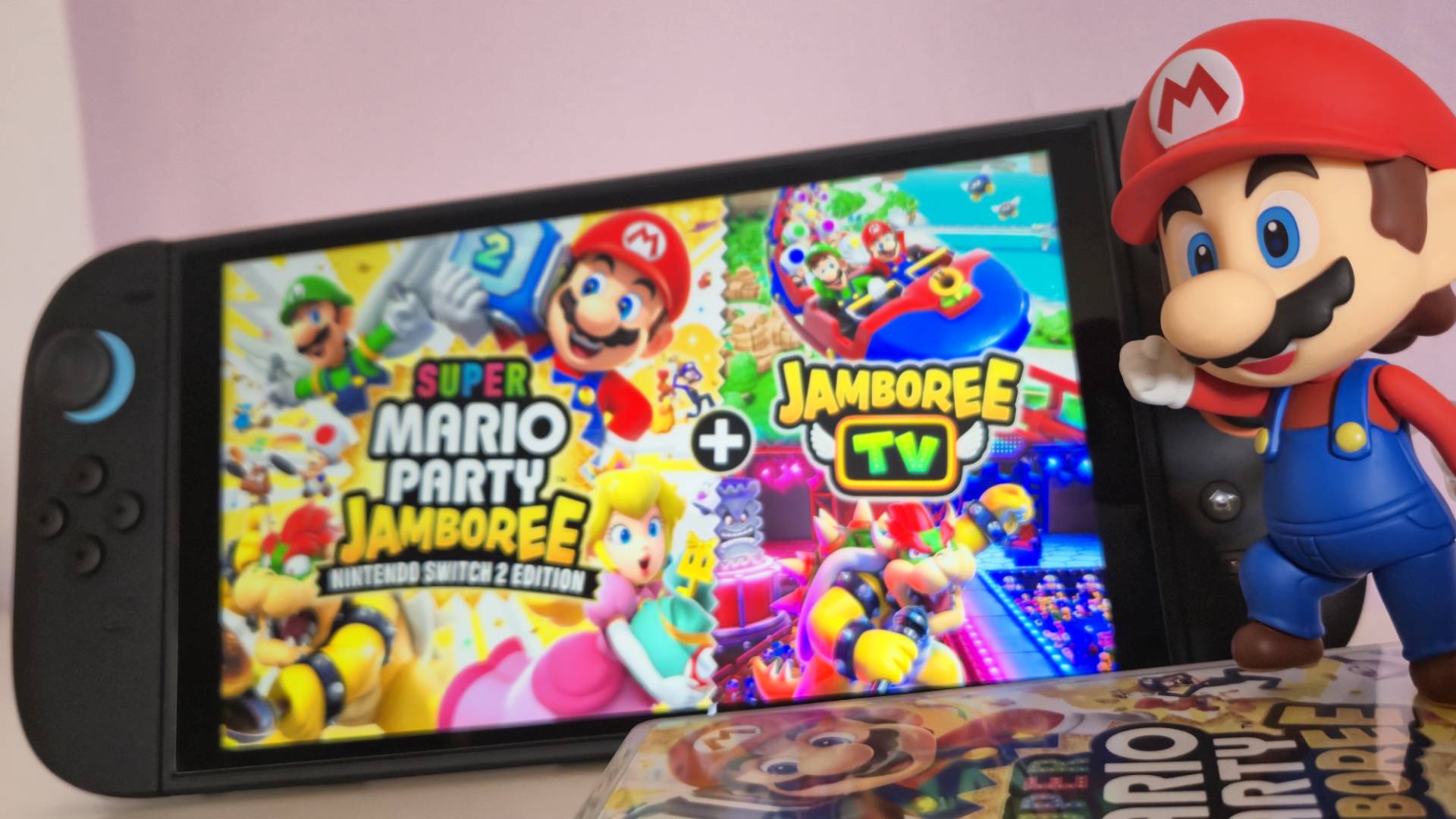 Photo by Rosalie Newcombe of Super Mario Party Jamboree Switch 2 Edition running on the Switch 2 with the Good Smile Company Mario Nendoroid figure standing off to the right hand side of the screen.