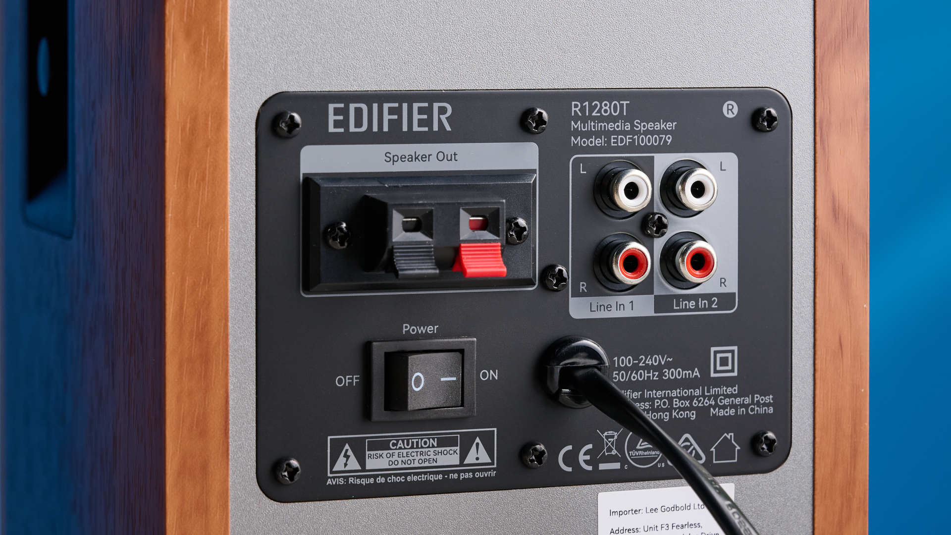 the edifier r1280t bookshelf speakers in wood brown photographed against the blue background, showing the volume adjustment dials, internal drivers and tweeters, RCA and aux inputs, and remote