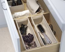 A bathroom drawer with canvas drawer dividers creating individual compartments for cosmetics