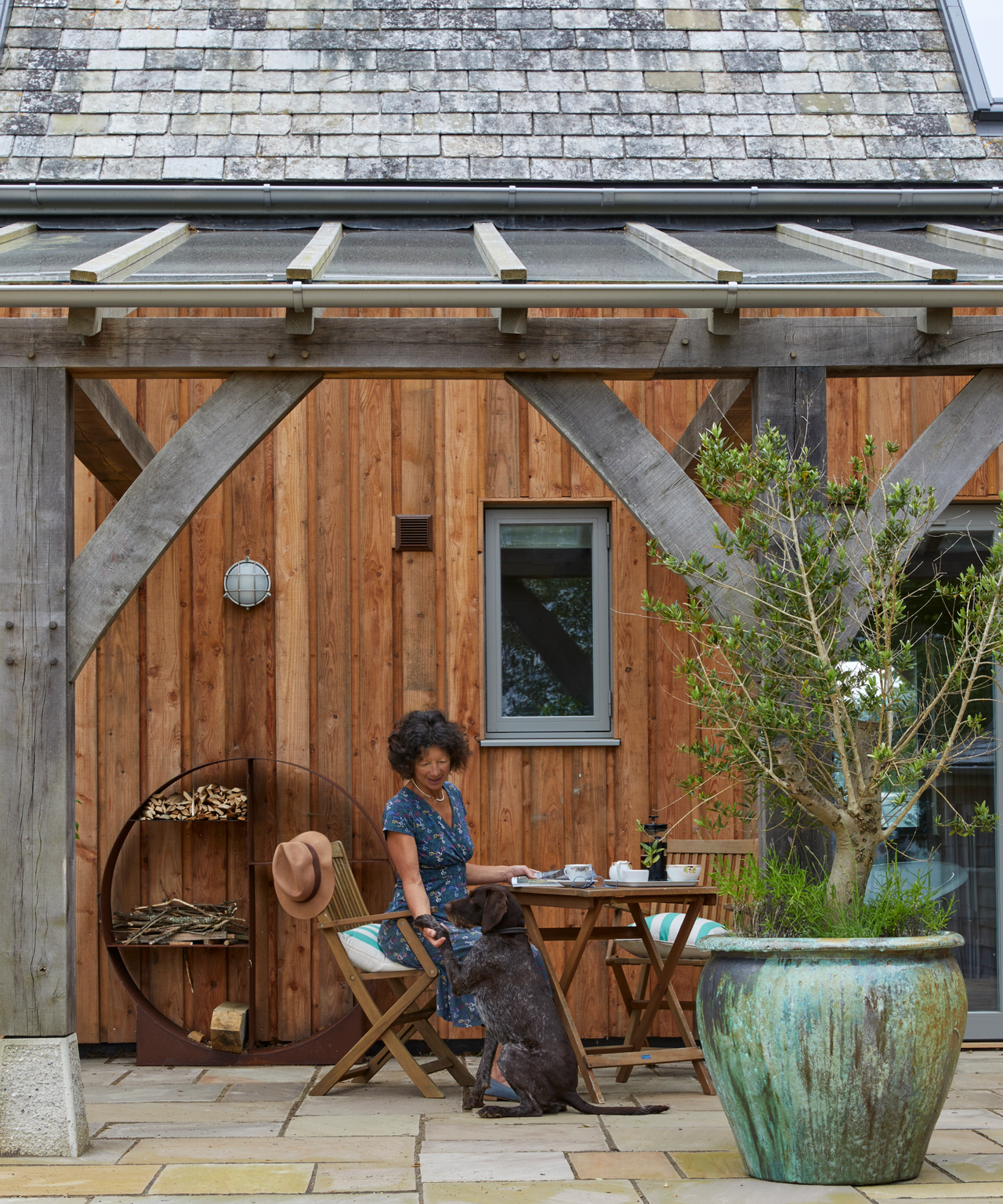 Woman sitting on the chair under the veranda with a dog