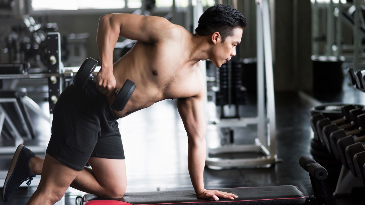 Athletic person doing one arm rows using dumbbells