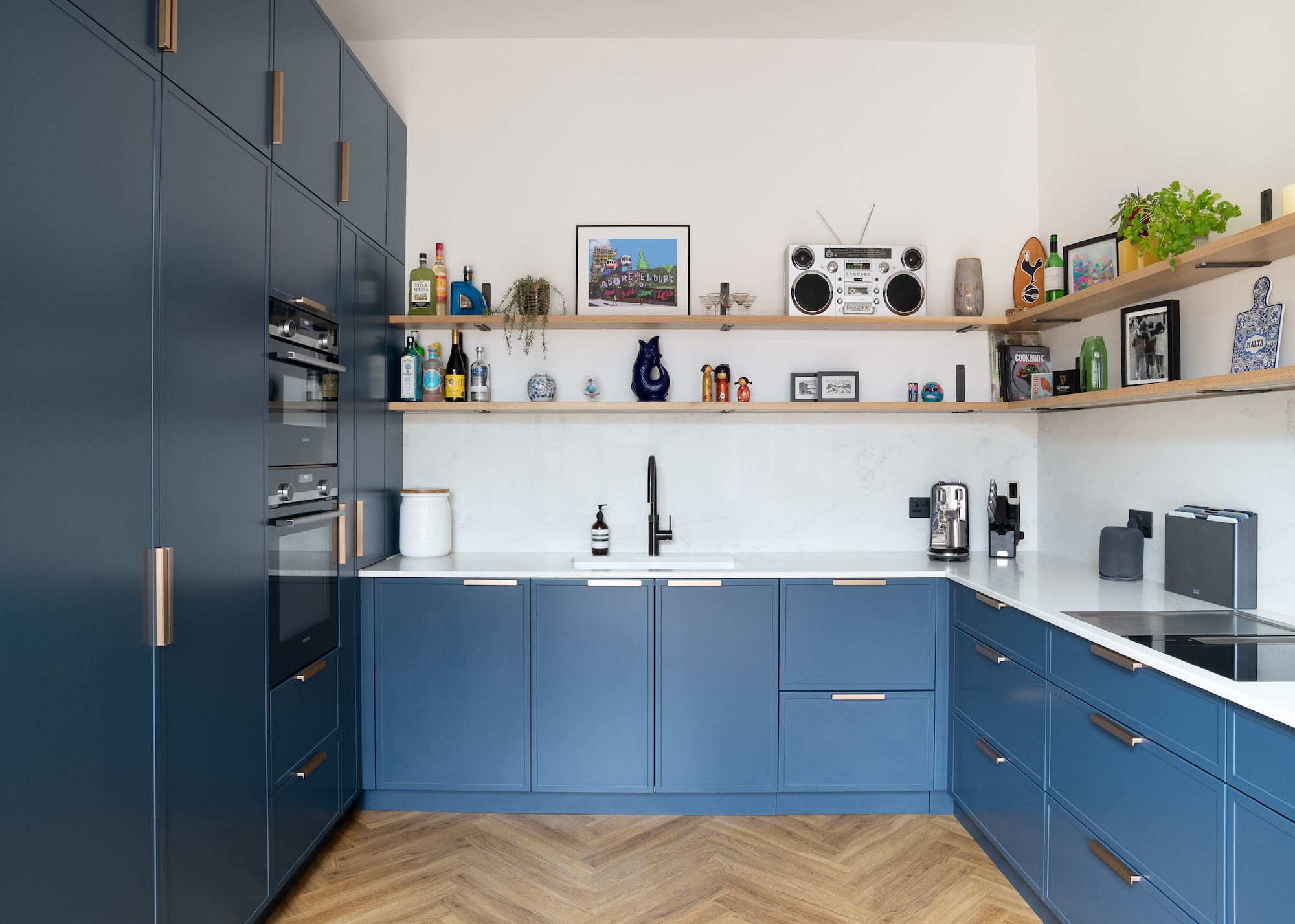 A blue kitchen with floor to ceiling storage as well as lower cabinets and open shelving above the cabinets and countertops.