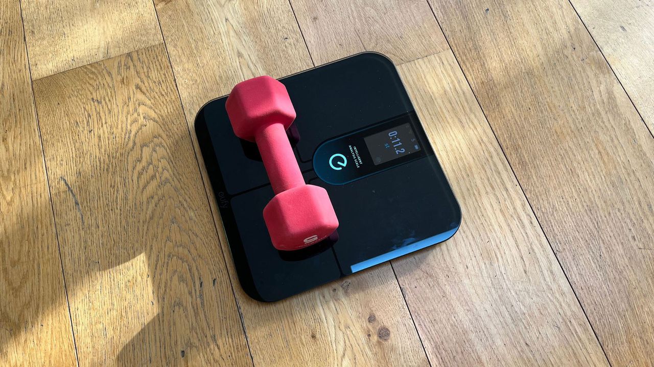 Eufy P3 smart scale weighing a small dumbbell