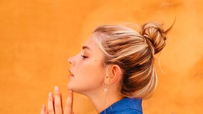 Woman with hair bun against yellow wall - stock photo