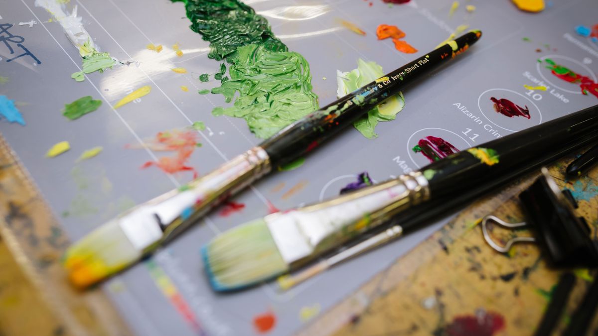 A metal can with a set of brushes for painting in an art workshop